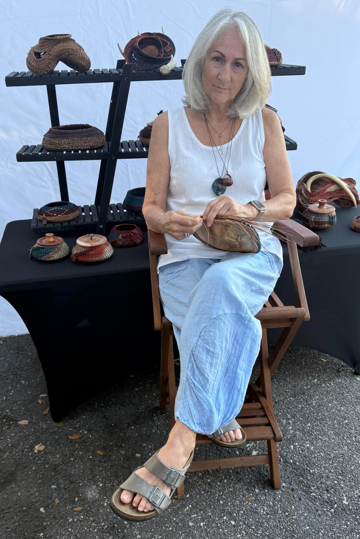 Sheree weaving pine needle art surrounded by her handmade baskets
